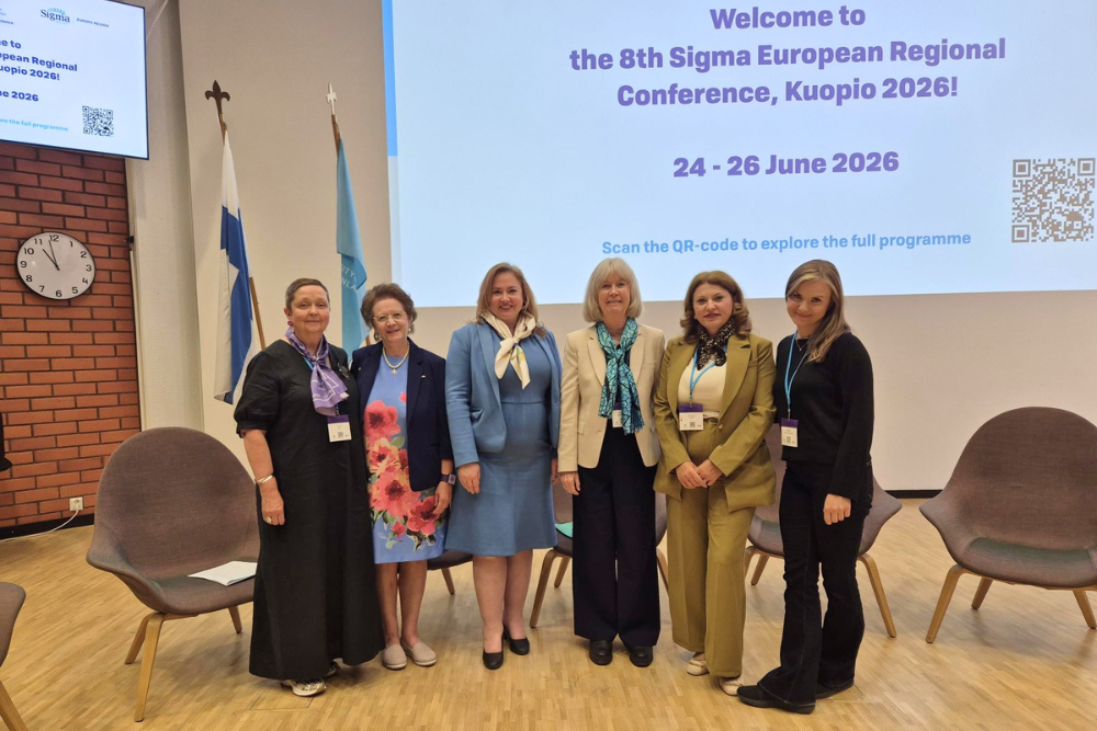 six women standing in front of a presentation screen at a conference