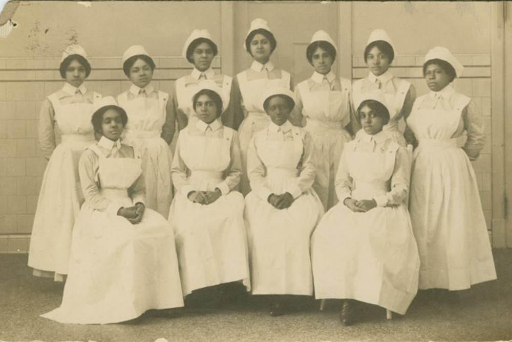 A group of female Black graduates in white nurses uniforms