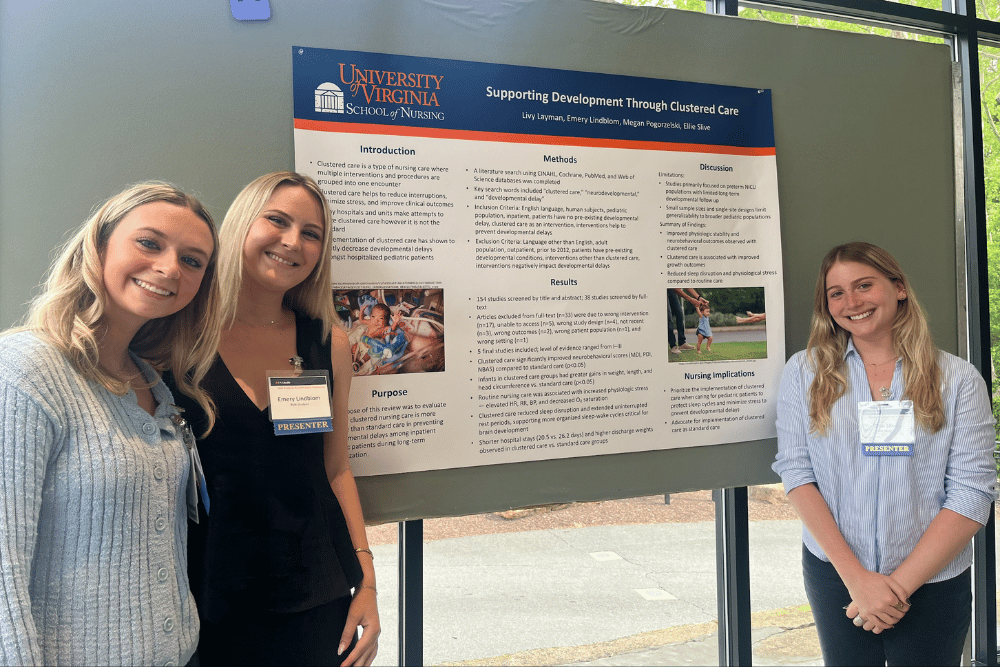 Three smiling students standing in front of a research poster
