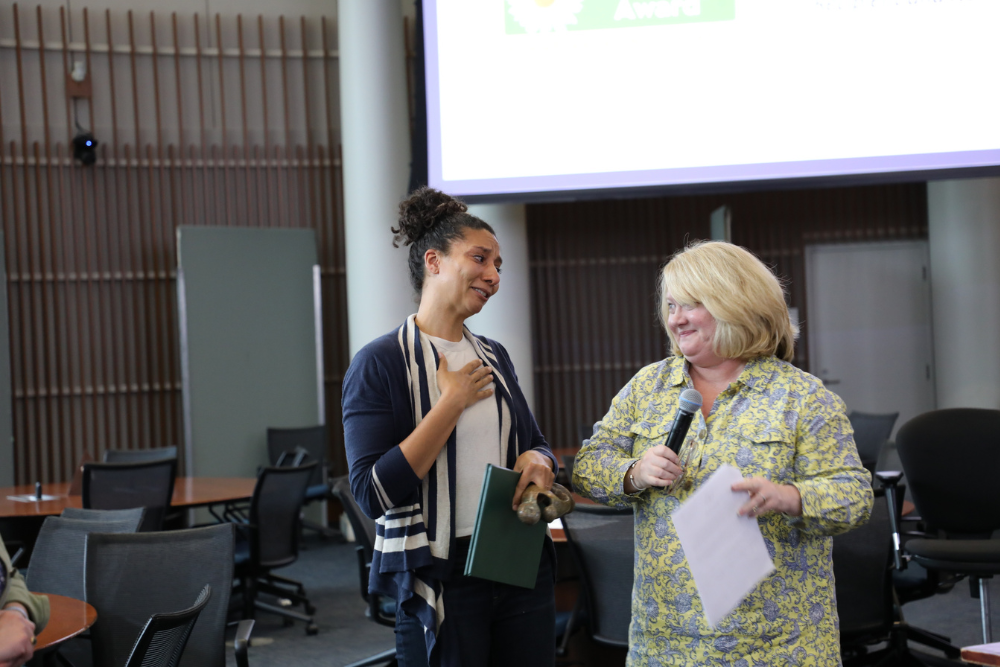 Two smiling women standing together in a conference room