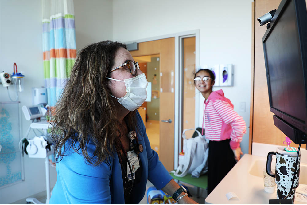 Preceptor Christy Murray inputs info into EPIC while sister Brooklyn looks on