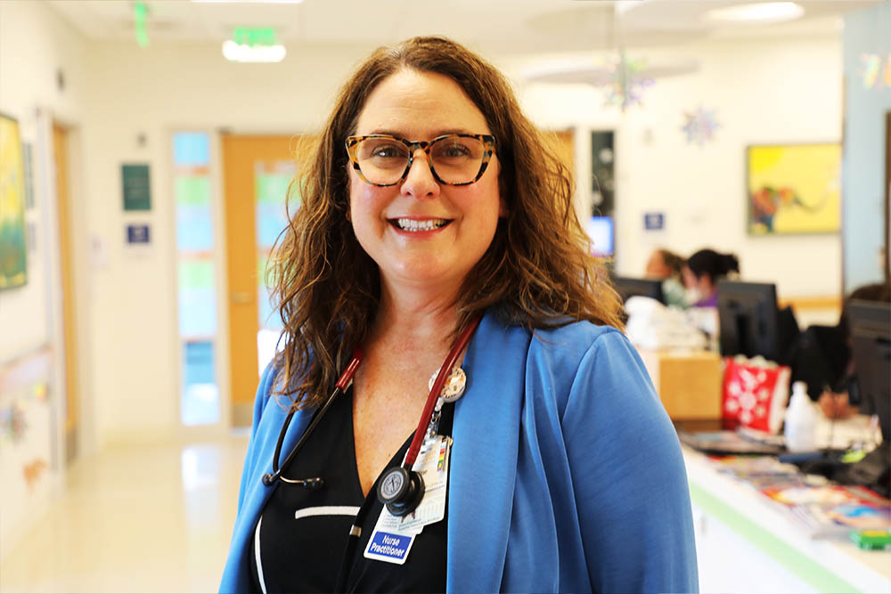 A pediatric NP poses in the hospital hallway.