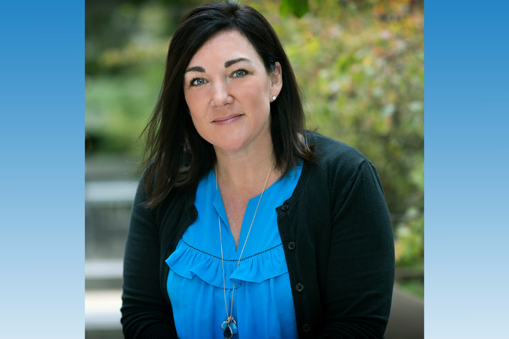 a woman in a blue shirt and black sweater smiling