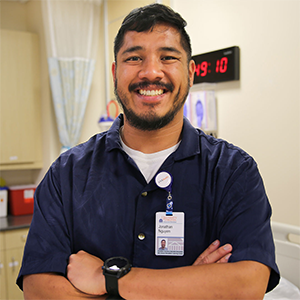 A man in dark blue scrubs smiling at the camera