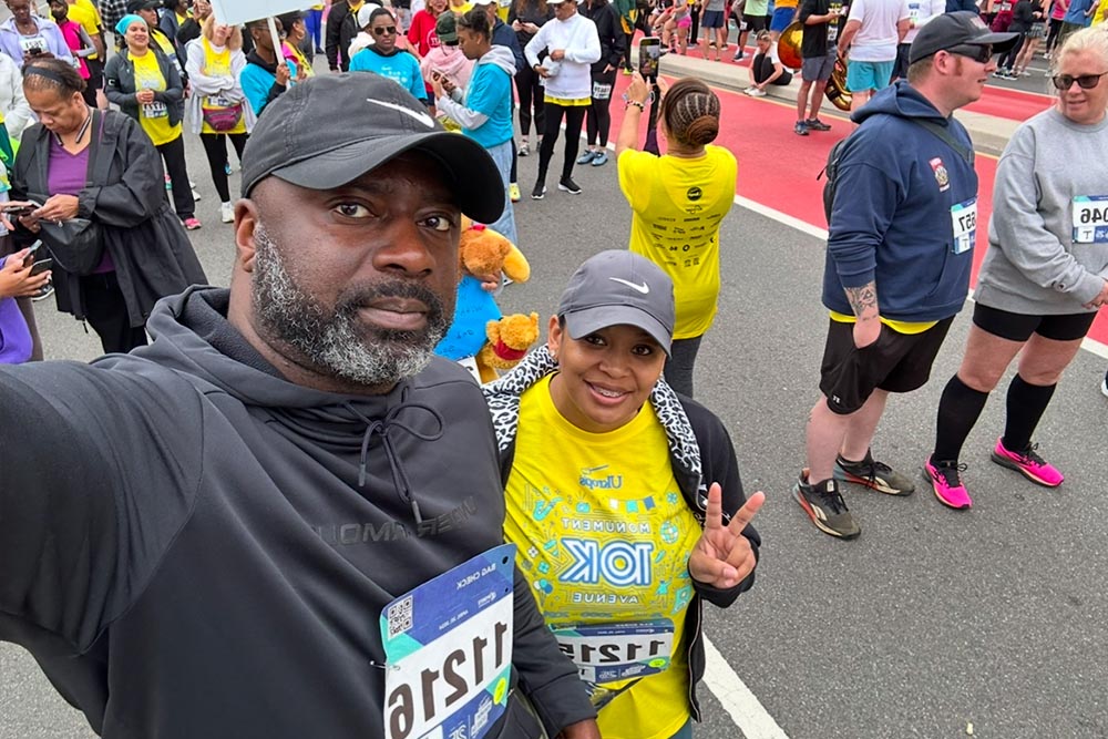 Two runners smile in a crowd after completing a foot race